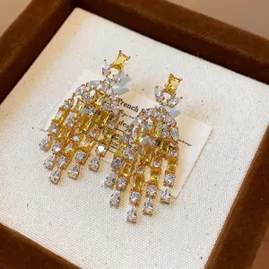 Primo piano di eleganti orecchini a nappine dorate con zirconi gialli e trasparenti