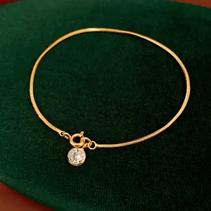 Nahaufnahme eines 18 Karat vergoldeten Schlangenarmbands mit rundem Zirkonia-Anhänger
