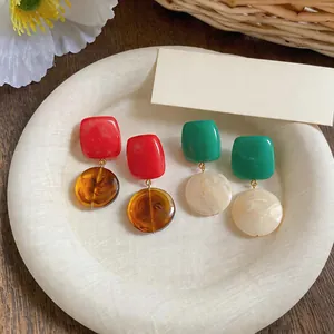 Close-up of vibrant resin geometric earrings with rectangle and round marble pendants