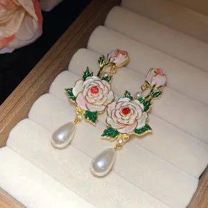 Gros plan sur des boucles d'oreilles rose en émail vintage avec perles élégantes