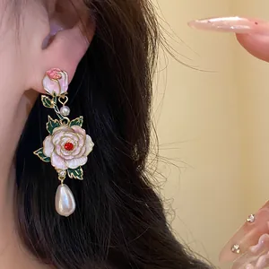 Détail d'une boucle d'oreille rose en émail vintage avec perle élégante et gemme rouge