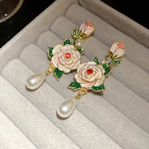 Vue détaillée des boucles d'oreilles rose en émail vintage avec perles poires sur velours gris