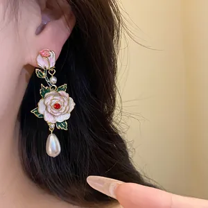 Gros plan de boucles d'oreilles rose émaillée vintage avec perle pendante sur l'oreille