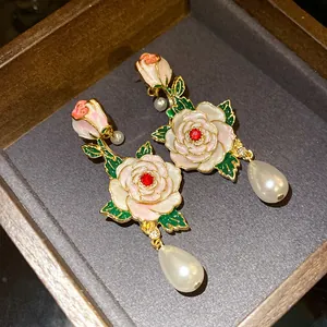Gros plan de boucles d'oreilles roses en émail vintage avec perles et cristaux