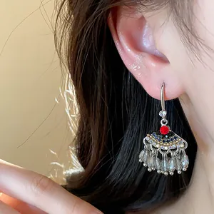 Détail de boucles d'oreilles ethniques vintage avec strass et glands de perles.