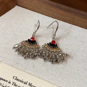 Vue détaillée de boucles d'oreilles vintage en éventail avec strass rouges et glands