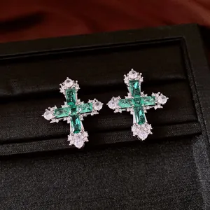Close-up of vintage cross stud earrings featuring brilliant green and clear zirconia stones