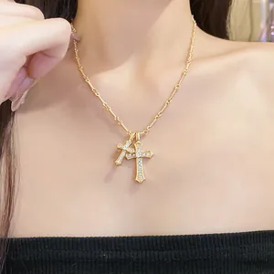 Close-up detail shot of elegant gold-plated double cross pendant necklace with zircons