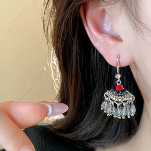 Vue détaillée de boucles d'oreilles ethniques avec cristaux rouges et glands de perles