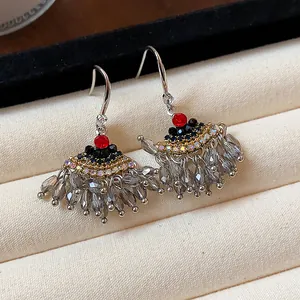 Gros plan de boucles d'oreilles ethniques vintage avec strass rouges et glands perlés gris.