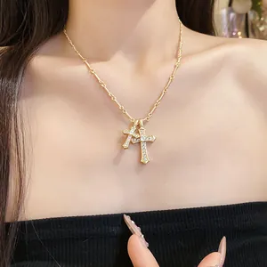 Detailed view of layered gold cross pendant necklace with zircon studs on a model