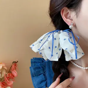 Elegant floral bow hair scrunchie with blue ribbons and pearl accents