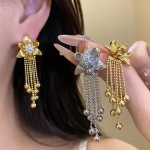 Detailed view of elegant flower earrings with zircon inlays and bead tassels in gold