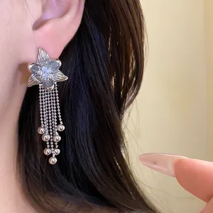 Detail of silver flower earrings with zircon center and beaded tassels on a model
