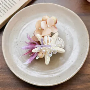 Close-up of a beach style hair clip with shell and fabric flowers on a ceramic plate