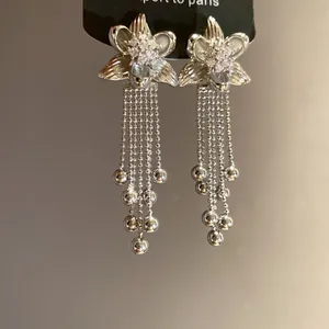 Close-up of silver-tone floral tassel earrings with cubic zirconia detail