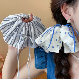 Detail view of large floral and striped scrunchies with elegant blue ribbon and pearl accent