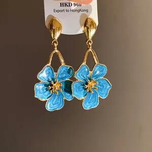 Close-up of elegant blue enamel flower drop earrings with gold-plated finish