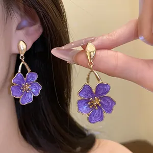 Close-up of purple oil drip flower earrings with retro golden details and texture.