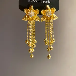 Close-up of 18k gold plated flower earrings with zircon center and beaded tassels