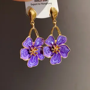 Detailed close-up of vintage purple enamel flower drop earrings with golden accents and metal trim.