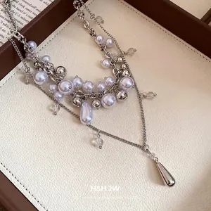 French multi-layer pearl necklace with silver chains and metallic teardrop pendant
