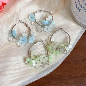 Dettaglio di orecchini a cerchio con fiori in resina in varianti blu e verde