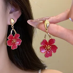 Detailed macro shot of elegant red enamel flower drop earrings with a vintage gold finish
