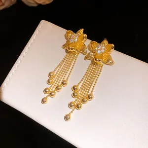 Detailed macro view of 18k gold plated flower earrings with zircon tassels and gold beads