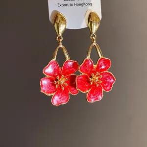 Detailed macro view of vintage red enamel flower drop earrings with golden metal finish