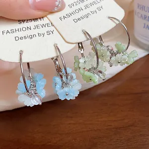 Primo piano dettagliato dei delicati ciondoli a fiore in resina opaca su orecchini a cerchio.