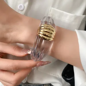 Elegante Detailansicht eines Manschettenarmbands aus klarem Harz mit Goldverzierung.