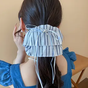 Detail view of an elegant blue striped bow hair scrunchie with long ribbons on hair.