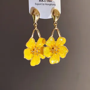 Detailed macro view of elegant vintage yellow enamel flower drop earrings with golden trim