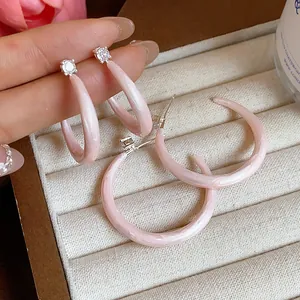 Vista de detalle de aretes de aro en C de esmalte rosa con circonitas brillantes