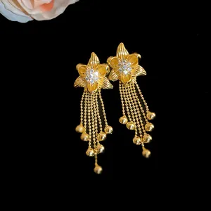 Detail of gold-plated flower earrings with shimmering zircons and beaded tassels