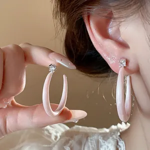 Primer plano de pendientes de aro en C de esmalte rosa con tachuelas de circón