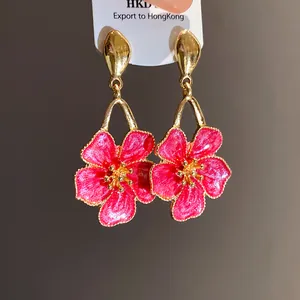Detailed macro view of vintage pink enamel flower drop earrings with gold-toned metal