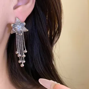 Close-up of silver flower tassel earrings with sparkling zirconia on a model's ear