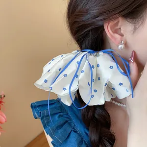 Close-up of an elegant white floral scrunchie with blue ribbons on a braided hairstyle.