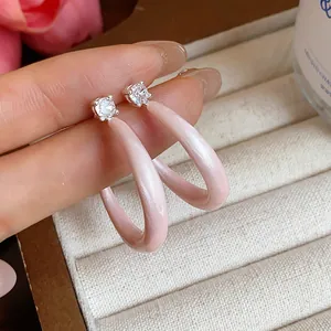 Primer plano de pendientes de aro en C de esmalte rosa con circonitas brillantes.