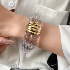 Detailansicht eines Manschettenarmbands aus transparentem Harz mit goldenem Mittelstück.