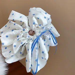 Detailed view of high-quality cream floral scrunchie featuring blue ribbon and pearl charms