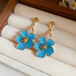 Elegant blue floral enamel drop earrings displayed in a soft cream velvet jewelry box