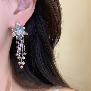 Close-up of elegant 18k gold plated flower earring with zircon and tassel drops on a model
