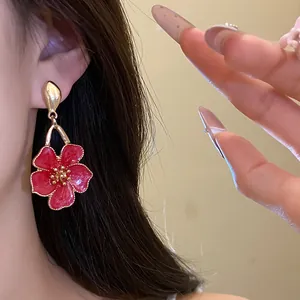 Detail of vintage red enamel flower pendant earring with gold trim on model's ear