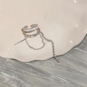 Macro detail of silver-tone double-layered ear cuff with cubic zirconia and tassels
