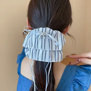 Detailed view of a blue striped fabric scrunchie with a silver bow and long ribbons.