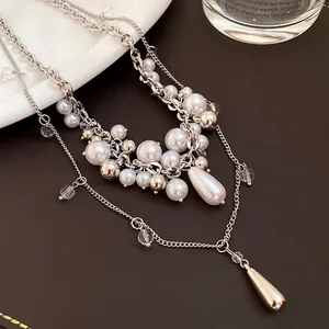 Close-up detail of a French layered necklace with pearls and silver teardrop pendants.