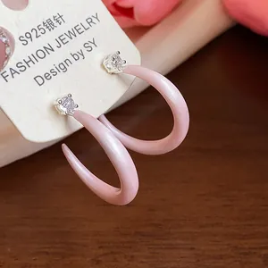 Primer plano de pendientes en C de esmalte rosa con circonitas y agujas de plata S925.